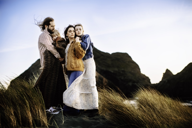 Family Photographer, a family of four huddle together on a dry grassy mountainside