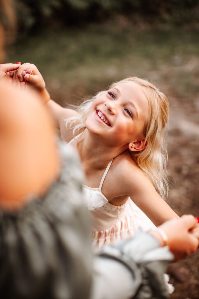 Family Photographer, a little girl smiles as she looks up to her mother